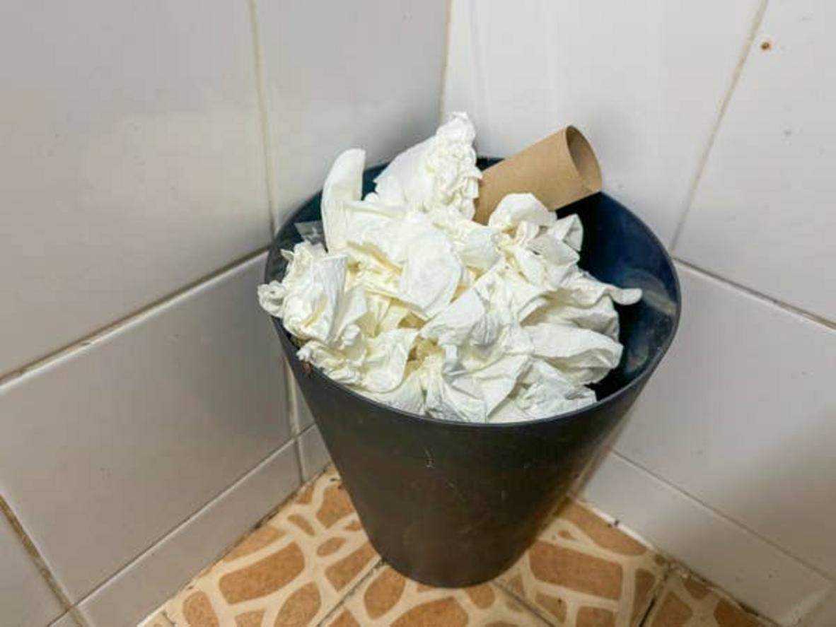 Papelera de baño llena de papel higiénico