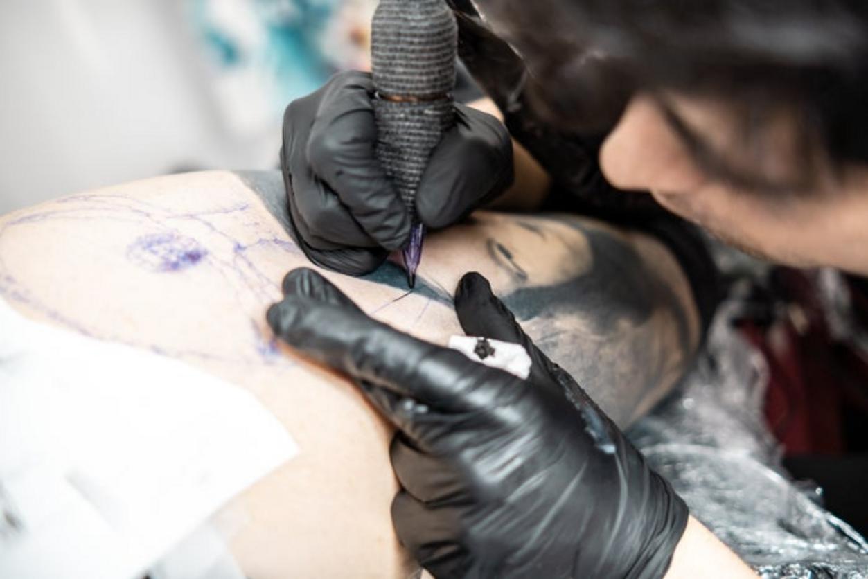 Tatuador trabajando en un diseño en el brazo de un cliente