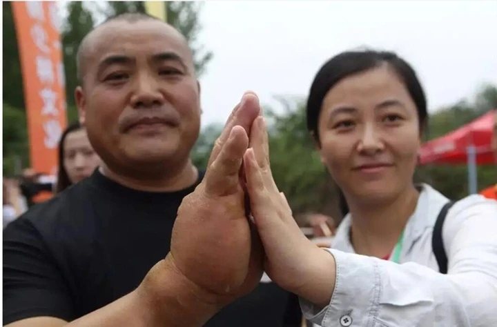 Maestro de kung-fu chino comparando su palma extremadamente gruesa con la mano de tamaño normal de una mujer