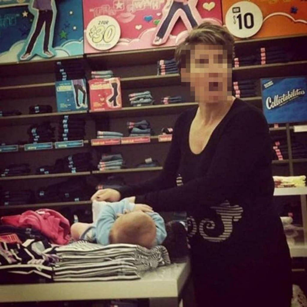 Mujer cambiando un pañal sobre la ropa en una tienda