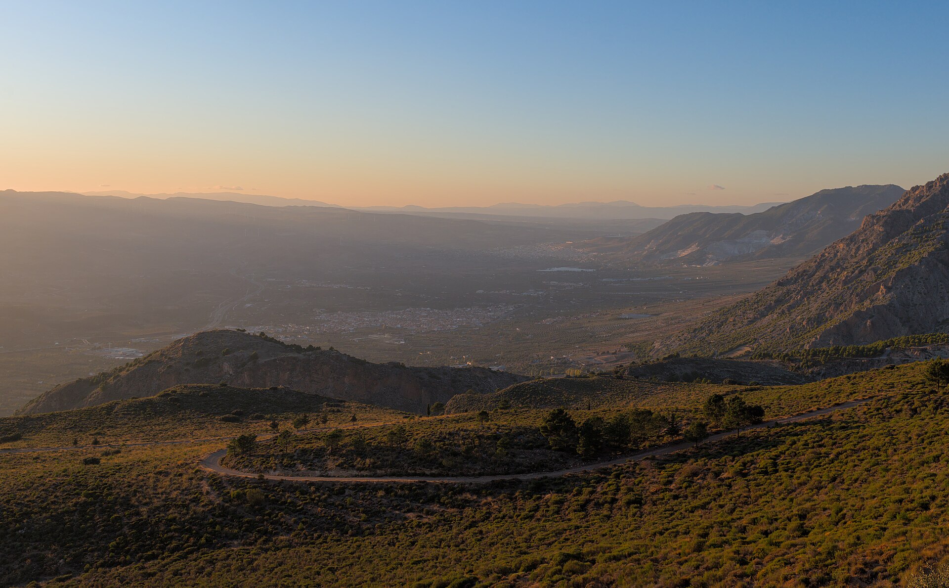 Vista del valle de Lecrín al atardecer, con el pueblo de Dúrcal y campos de cultivo entre montañas de Granada