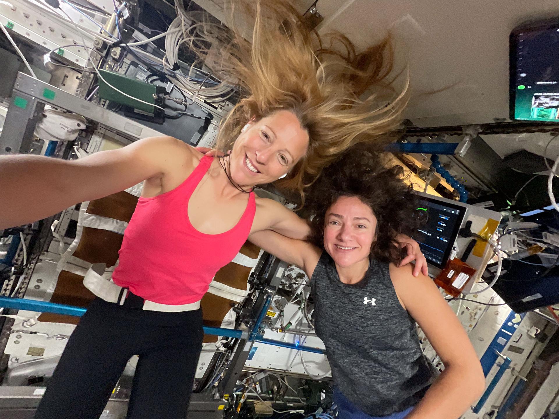 Sophie Adenot y la astronauta Jessica Meir, con ropa deportiva y el pelo flotando, antes de una sesión de ejercicio en la Estación Espacial Internacional