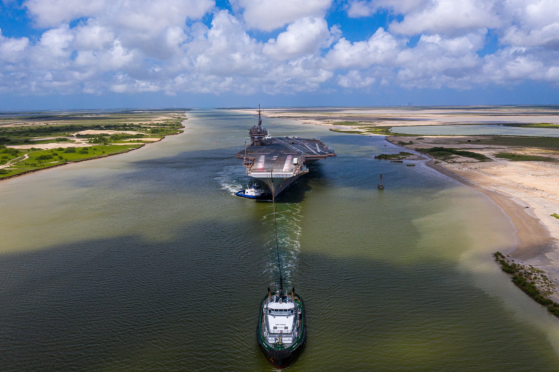 El portaaviones Kitty Hawk, vacío y sin aviones, remolcado por un remolcador Foss por el canal de Brownsville