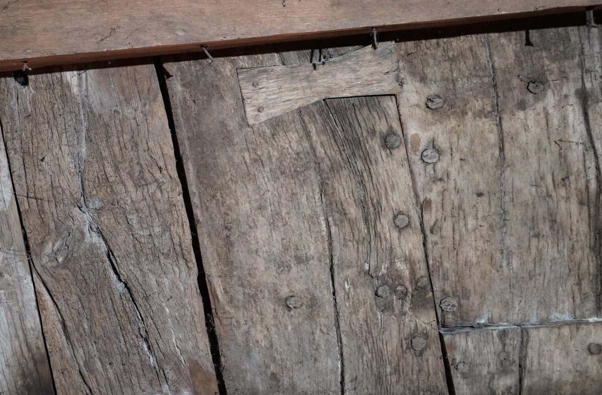 Tablones de madera muy antiguos con hileras de clavos de madera y una pieza encajada a modo de remiendo