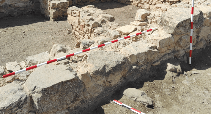 La cabeza ibérica de piedra caliza, semienterrada junto a la base del muro de mampostería del granero romano de Libisosa