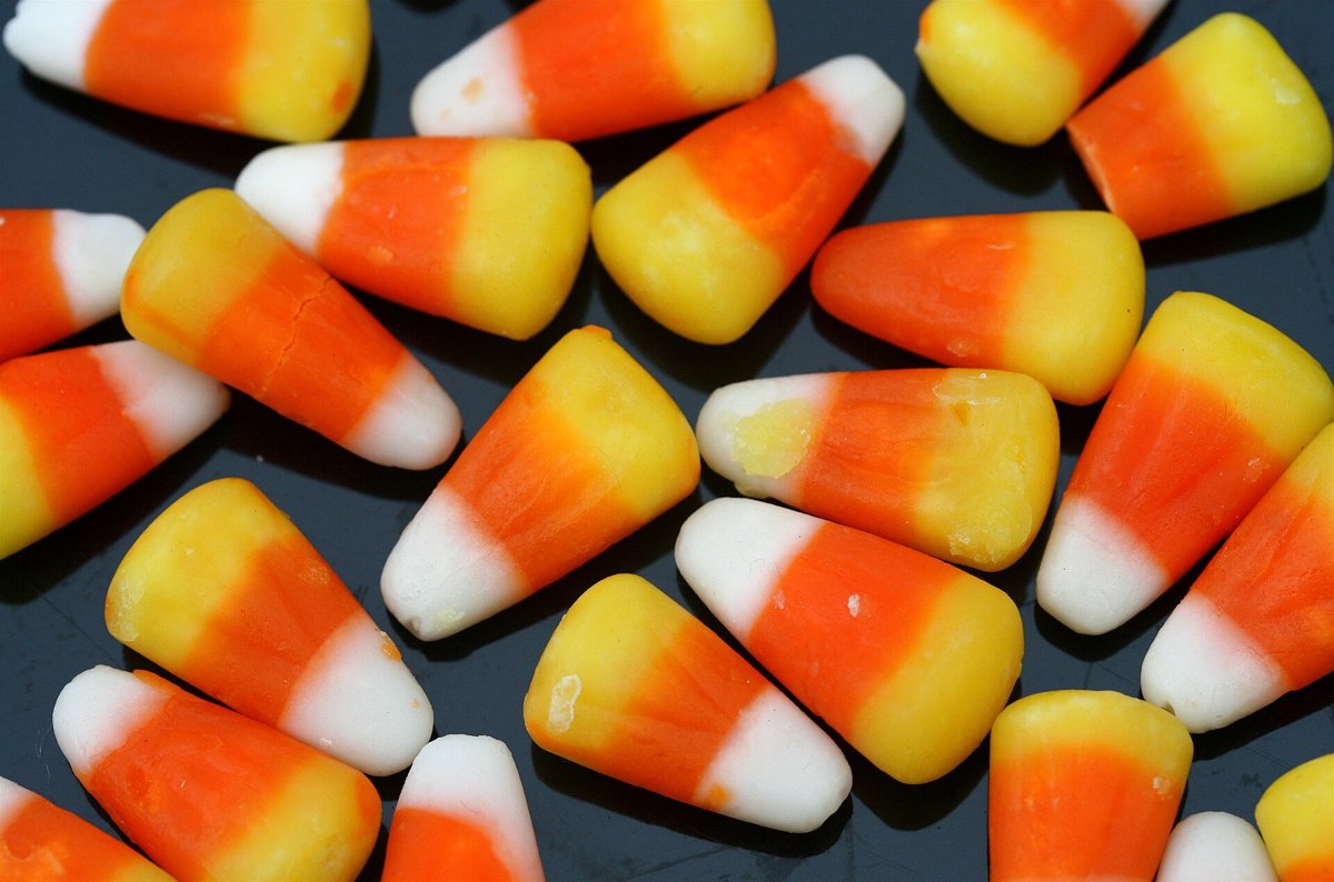 Granos de candy corn esparcidos sobre fondo oscuro, con sus franjas blanca, naranja y amarilla vistas de cerca